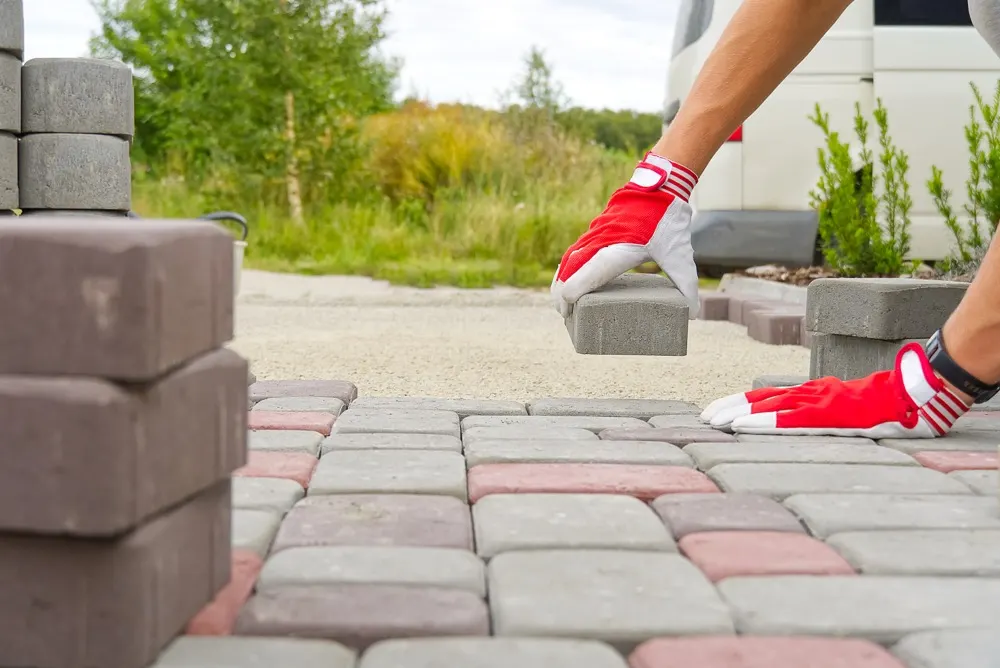 Block paving going down on a new driveway, blocks stacked ready.