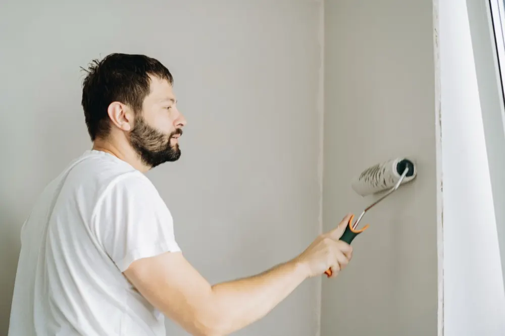 A decorator rolling paint onto an interior wall.